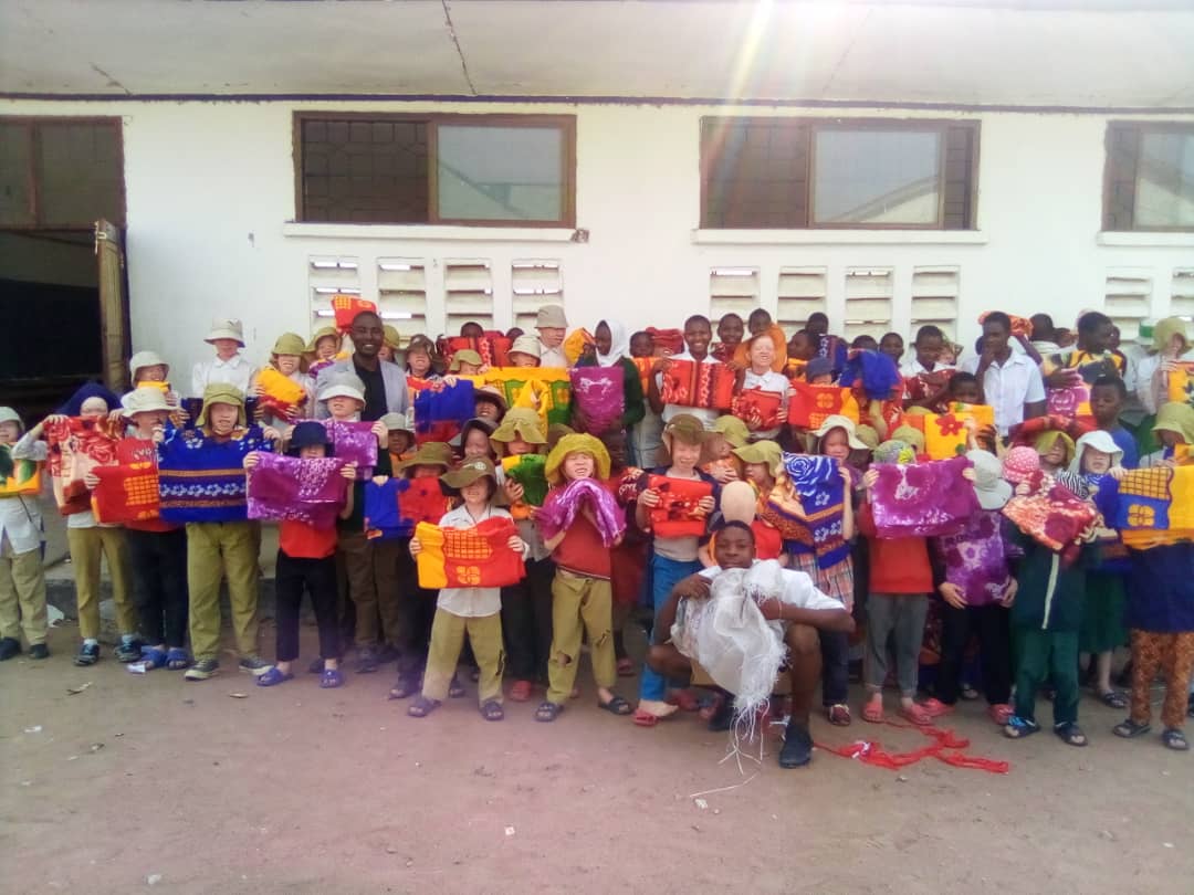 A large group of children at Mitindo holding up colorful new blankets